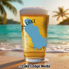 Glass of beer with Washington State shape on beach at sunset