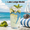 Glass with beverage, limes, mint, and compass design on a beach background.