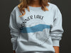 Light blue sweatshirt with "Donner Lake California" text and compass graphic.