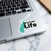 Saratoga Life sticker on a laptop keyboard, with a turquoise map outline.