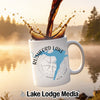 White mug with Rushford Lake and compass design, coffee pouring into it.
