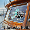 Teal lake outline sticker over "Little Grassy Life" on boat window, "Lake Lodge Media" text below.