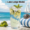 Glass with "Lake Cachuma California" design next to limes on beach background.