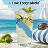 Glass of lemonade with limes, mint, and ice on a beach with sailing boat.