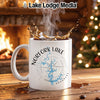 White mug with "Norfolk Lake Arkansas" design and splashing coffee in a cozy setting.