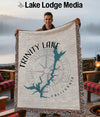 Man holding Trinity Lake California map blanket with compass design and fringed edges.