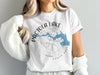 White t-shirt displaying "Pactola Lake" over a compass with South Dakota map.