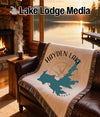 Woven blanket with Hayden Lake, Idaho map and compass design on a couch.