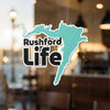 Rushford Life sticker with a teal outline in the shape of a map over blurred background.