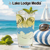 Glass of citrus drink with ice, mint, and lime on table with beach background.