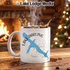 White mug with blue lake outline and compass, steaming coffee splashes.