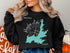 Black sweatshirt with "Beautiful Hayden Lake Idaho" compass design.