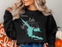 Black sweatshirt with turquoise map graphic and compass on chest.