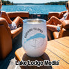 A white insulated wine tumbler with a Kiawah Island graphic sits on a wooden boat table.