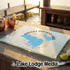 Glass cutting board with Brooks and Hess Lake Michigan graphic resting on outdoor wooden bar.