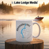 White mug with "ABRAHAM LAKE ALBERTA" and compass design on a lake background.