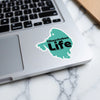 Turquoise sticker with "Okeechobee Life" text on a laptop keyboard.