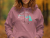 Rose hoodie with a compass graphic and a turquoise outline of South Dakota.