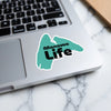 Teal Manawa Life sticker on a laptop keyboard.