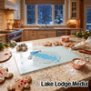 A glass cutting board with a Gull Lake map design sits on a kitchen counter amid baking supplies.