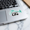 Flagstaff Life sticker on a laptop, with white outline and turquoise map shape.