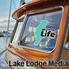 Teal Winnebago Life sticker on a wooden boat window with Lake Lodge Media logo.