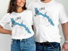 White t-shirts featuring a blue outline of Bass Lake, California, with compass details.