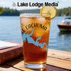 Iced tea glass with Lake Cachuma map graphic on a wooden table by a lake.