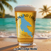Glass of beer with "Wfound Lake" and compass design on beach background.