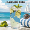 Clearwater Lake drink glass with ice, lime, and mint on beach with sailboat.