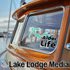 Boat window displays "Alder Life" sticker and "Lake Lodge Media" logo.