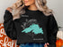 Black sweatshirt with teal outline of Lake Superior and compass rose.