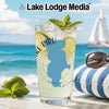 Tall glass of citrus drink with lime slices and mint on a beach with sailboat.