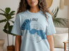 Light blue t-shirt with blue Forest Lake shape and compass on front.