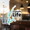 Smithville Life sticker with a teal lake outline on a glass surface.