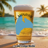 Glass of beer on a beach with "KE MANAWA" text and a blue map outline.