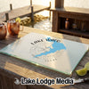A rectangular glass cutting board printed with a blue map of Lake Waco and a compass rose rests on a wooden table beside a dock.