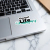 Sticker with "Channel Life" text and turquoise wavy design on a laptop.