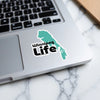 Winnipeg Life sticker on a laptop keyboard, green map shape.