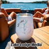 A white insulated wine tumbler with a Lay Lake Alabama map and compass design sits on a boat table.