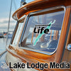 Logo on boat window reads "greenwood Life" with a teal lake outline and "Lake Lodge Media" text below.