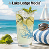 Glass with drink, lime, mint, sunglasses, beach scene, and Lake Lodge Media text.
