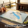 A glass cutting board featuring a blue map of Grapevine Lake, Texas, sits outdoors on a wooden table near a dock.