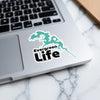 Evergreen Life sticker with teal lake outline on a laptop.