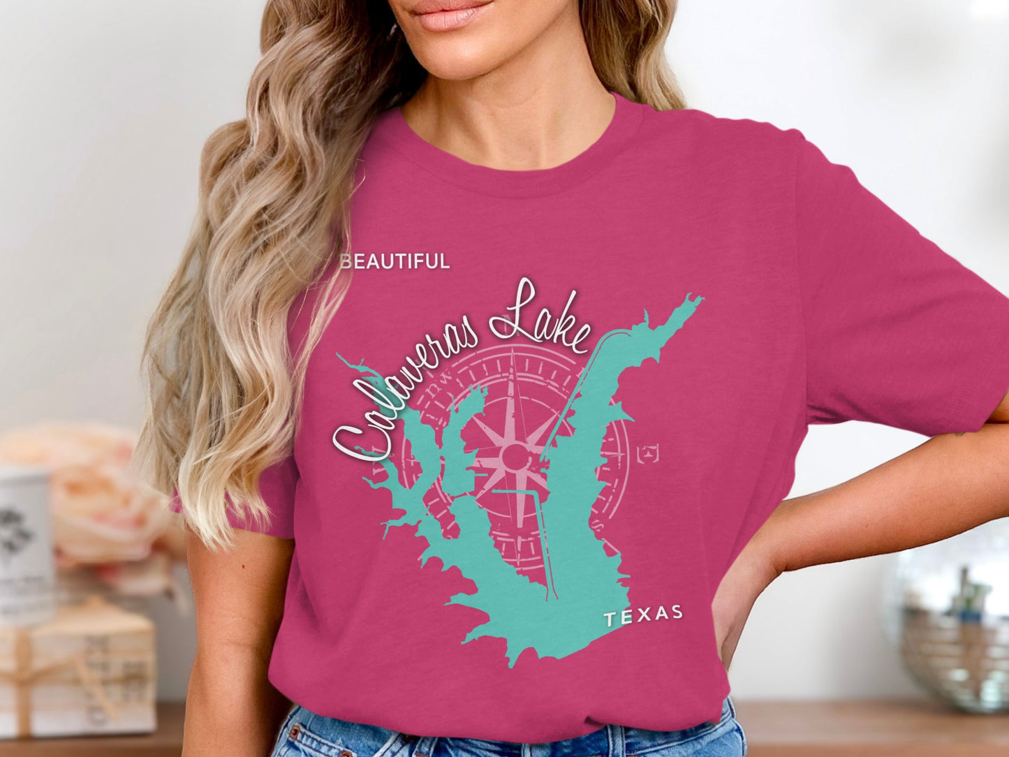 Teal map of Lake Calaveras, Texas with compass rose graphic on pink t-shirt.