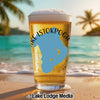 Glass of beer with "Lake Istokpoga" and Florida map graphic on a beach.