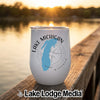 A white stemless tumbler featuring a Lake Michigan map graphic rests on a wooden dock at sunset.