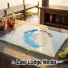 A rectangular glass cutting board featuring a blue map of Arkabutla Lake, Mississippi, rests on a wooden dock with drinks.
