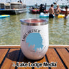 A white insulated wine tumbler with a Lake Hefner map graphic rests on a wooden boat deck with people swimming in the lake behind it.