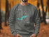 Grey sweatshirt with teal Shoal Lake map and compass rose design.